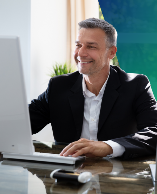 A middle-aged man in a suit at a desk smiling at computer screen, business owner, business rates assessment